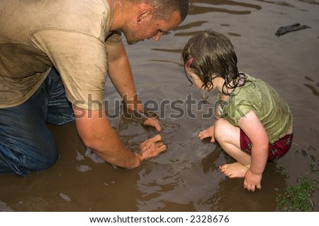 a Father and daughter playing in the mud