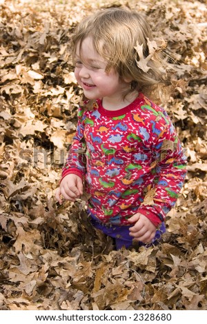 a little girl playing in a pile of leaves