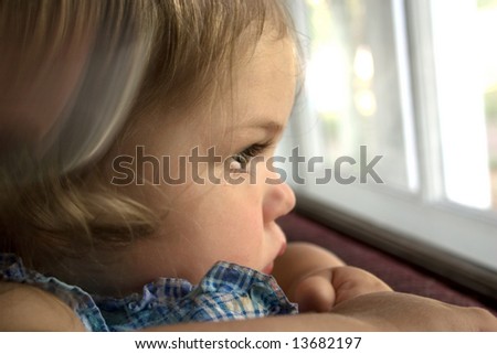 A little girl looking out a window with a tear running down her face