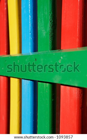Colourful rows of painted wood on a playground fence with yellow, green blue and red colors