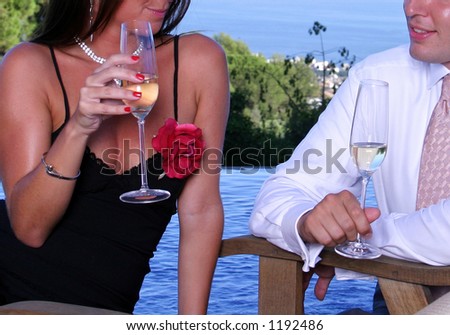 Smartly dressed couple with Champagne chatting at a dinner party next to a swimming pool