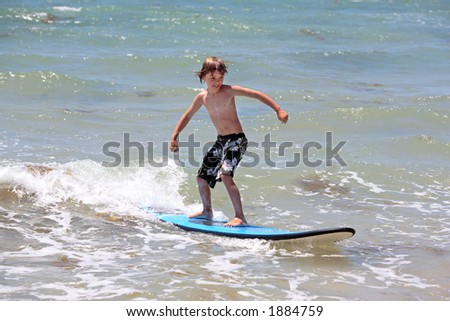 Healthy young boy learning to surf in the sea or ocean
