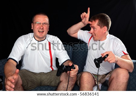 Two England football supporters playing soccer on a games console with handsets
