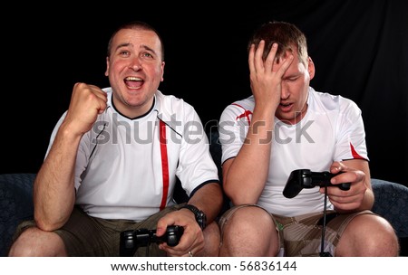 Two England football supporters playing soccer on a games console with handsets