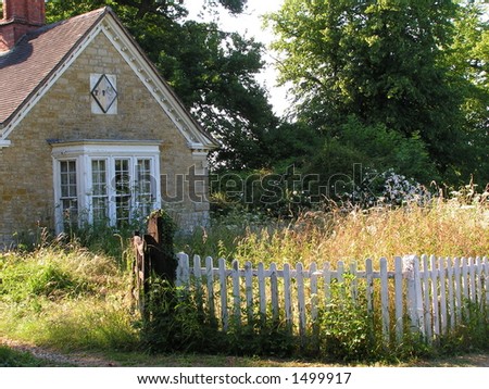 Overgrown garden, weeds and picket fence outside estate gatehouse.