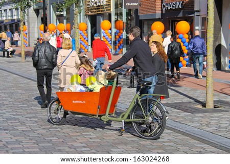 DORDRECHT, THE NETHERLANDS - SEPTEMBER 28:Young parents carry children in the bicycle stroller by celebratory street on September 28, 2013 in Dordrecht, Netherlands