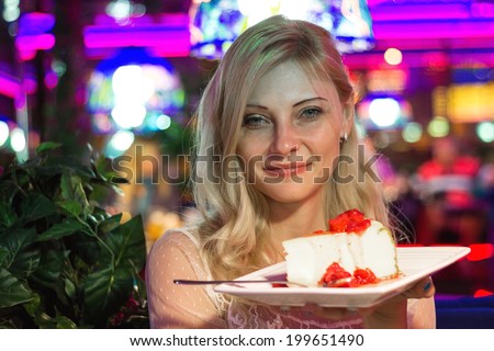 Attractive girl in night cafe keeps dessert