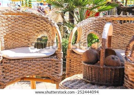 Wicker furniture and basket with coconut on the beach