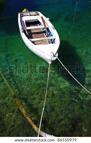White berthed fishing boat on the emerald sea with the reflection on the seabed