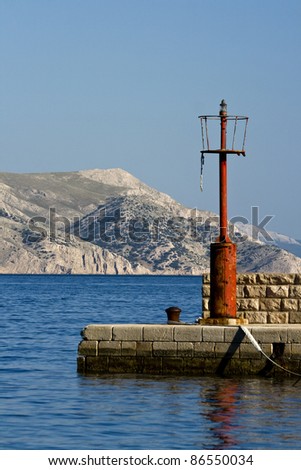 Red lighthouse at the end of the pier and the barren land island