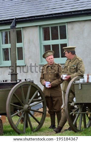 STOWE MARIES  AIRFIELD ESSEX UK FLYING DAY: May 14 2014,  Two men in World war one uniform by a carriage  enjoying  a cup of tea