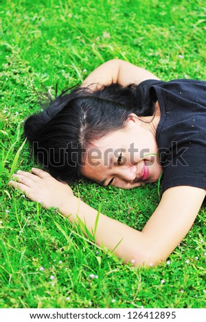 young asian woman laying down in grass