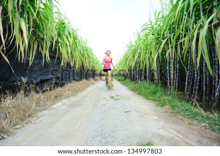young asian woman running in sugarcane field