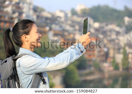 young asian woman use digital tablet taking photo at fenghuang ancient town,china