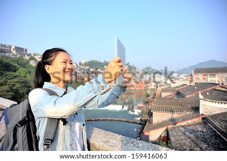 woman tourist use tablet pc taking photo at fenghuang ancient town,china
