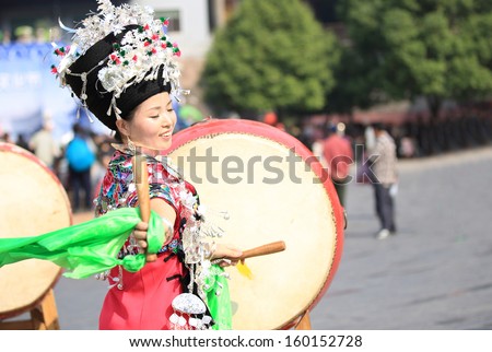 FENGHUANG - OCT 13:Miao nationality womon wearing silver accessories on hair and clothes beats a drum to celebrate the local festival in fenghuang ancient town on Oct 13, 2013 in Fenghuang,China.