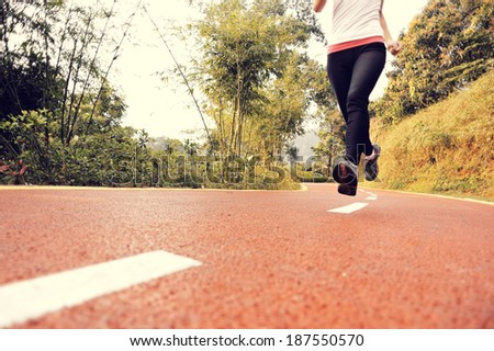 runner athlete feet running on road. woman fitness jogging workout wellness concept