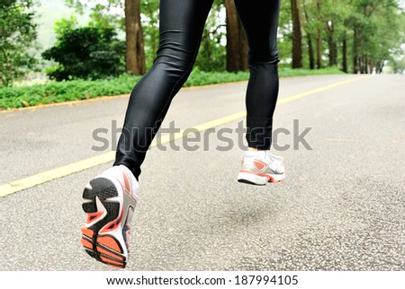 runner athlete feet running on road. woman fitness jogging workout wellness concept