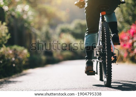 Woman riding a bike on tropical park trail in spring Imagine de stoc © 