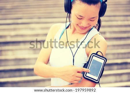 Runner athlete listening to music in headphones from smart phone mp3 player smart phone armband.woman fitness jogging workout wellness concept.