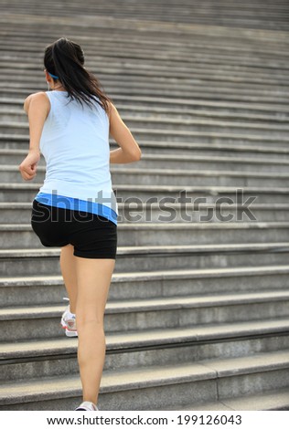 Runner athlete running on stairs. listening to music in headphones from smart phone mp3 player  woman fitness jogging workout wellness concept.