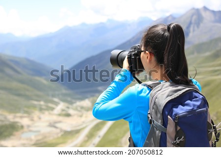 woman photographer taking photo at plateau mountain peak in tibet,china