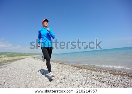 Runner athlete running on stone beach of qinghai lake. woman fitness ogging workout wellness concept.