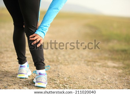 woman runner touch her sports injured calf training for marathon outdoor
