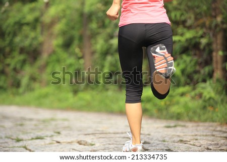 Runner athlete running on forest trail. woman fitness jogging workout wellness concept.