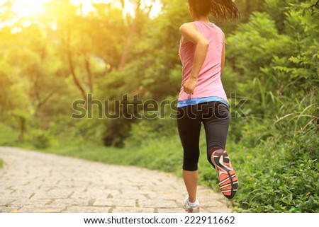 young fitness woman running at forest trail