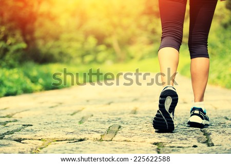 young fitness woman legs walking at forest trail