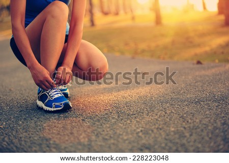 young woman runner tying shoelaces
