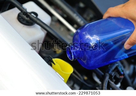 hands adding auto glass cleaner for car