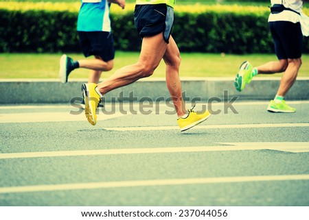 Unidentified marathon athletes legs running on city road