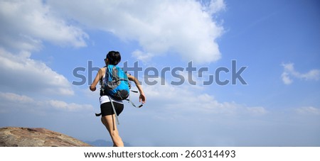 young asian woman hiker running from mountain peak to paradise