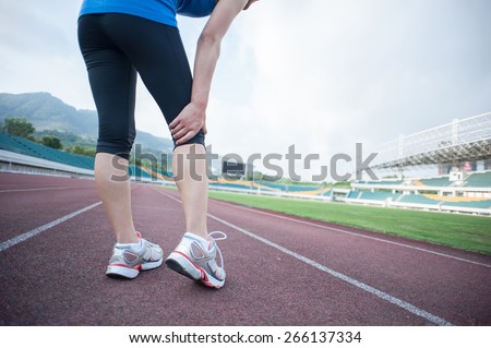 woman runner hold her injured leg on track