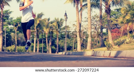 fitness jogger legs running at tropical park. woman fitness jogging workout wellness concept.