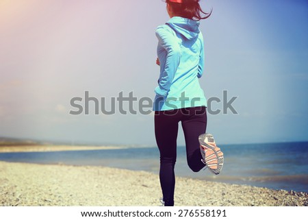 Runner athlete running on stone beach . woman fitness jogging workout wellness concept.
