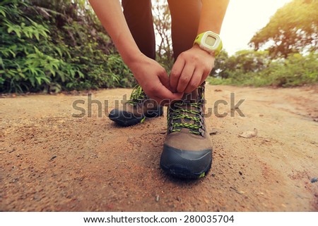 woman hiking tying shoelace on forest trail