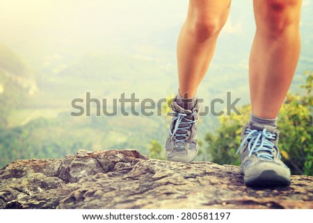 woman hiker legs climbing rock at mountain peak