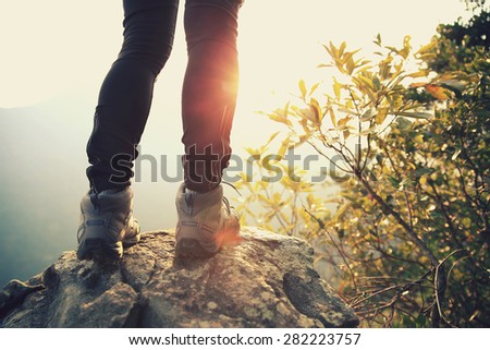 woman hiker legs stand on mountain peak rock