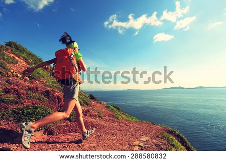 young woman backpacker walking on  seaside mountain trail
