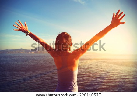 young cheering woman open arms at sunrise seaside