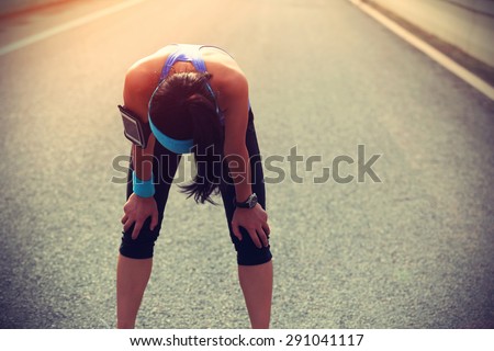 tired woman runner taking a rest after running hard on city road