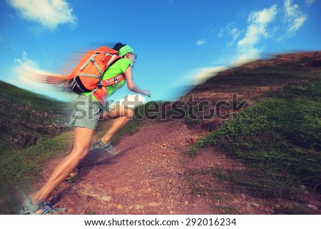 young woman backpacker running on mountain trail