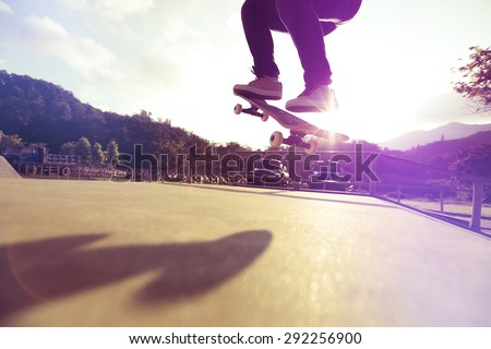 skateboarder legs doing a trick ollie at skatepark
