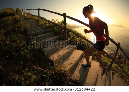 fitness woman trail runner running on seaside mountain stairs, training for cross country running.