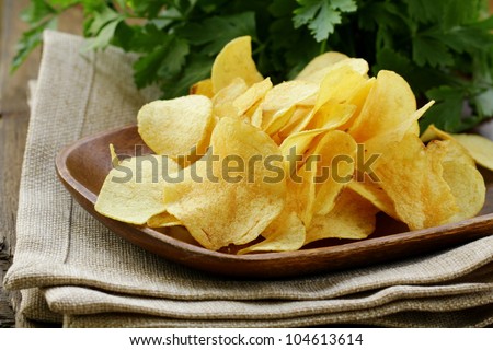 potato chips in wooden plate , on a wooden table
