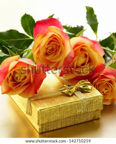 orange roses and box with gifts on gold background