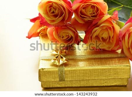orange roses and box with gifts on gold background